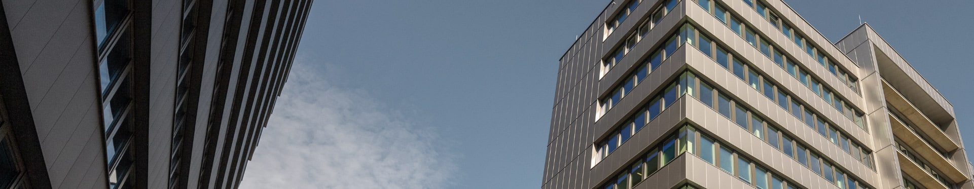 Moderne Bürogebäude mit Glasfassaden unter blauem Himmel.