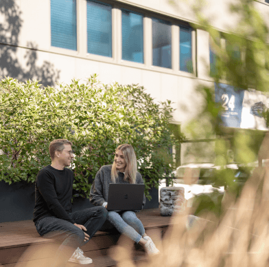 Moderne Bürogebäude-Fassade mit Menschen, die draußen sitzen und arbeiten.