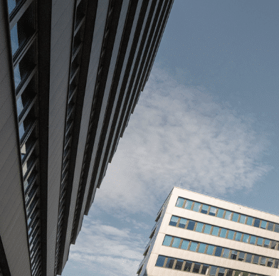 Moderne Bürogebäude mit Glasfassaden vor blauem Himmel.